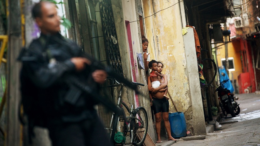 Residents look on as Brazilian military police officers patrol Mare, one of the largest complexes of favelas in Rio de Janeiro, Brazil, on March 30. - Mario Tama